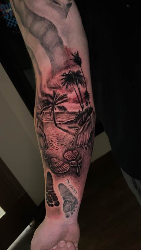 Black and grey beach scene sleeve with palms and footprints. Tattoo by a Thorn and Oath artist.