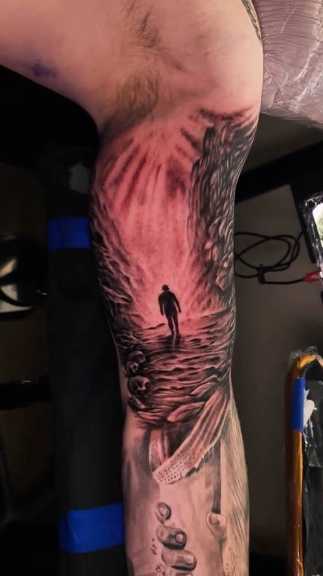Black and grey sleeve of a figure walking toward light. Tattoo by a Thorn and Oath artist.