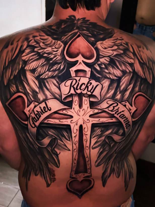 Black and grey back piece with a cross, banners and wings. Tattoo by a Thorn and Oath artist.