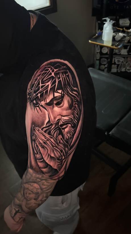 Black and grey portrait sleeve with praying hands. Tattoo by a Thorn and Oath artist.